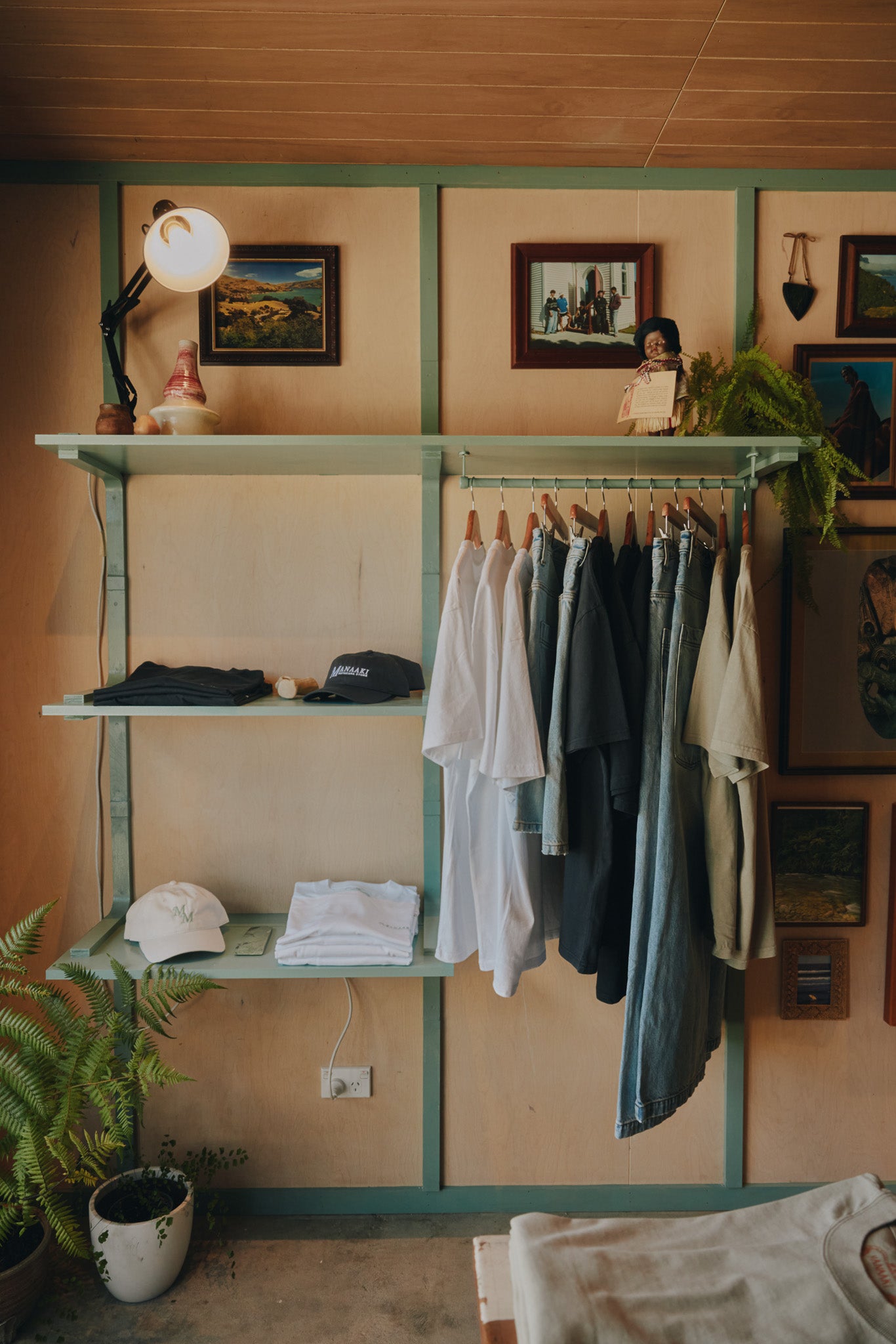 Clothing rack with shirts on a wall with shelves and decor items.