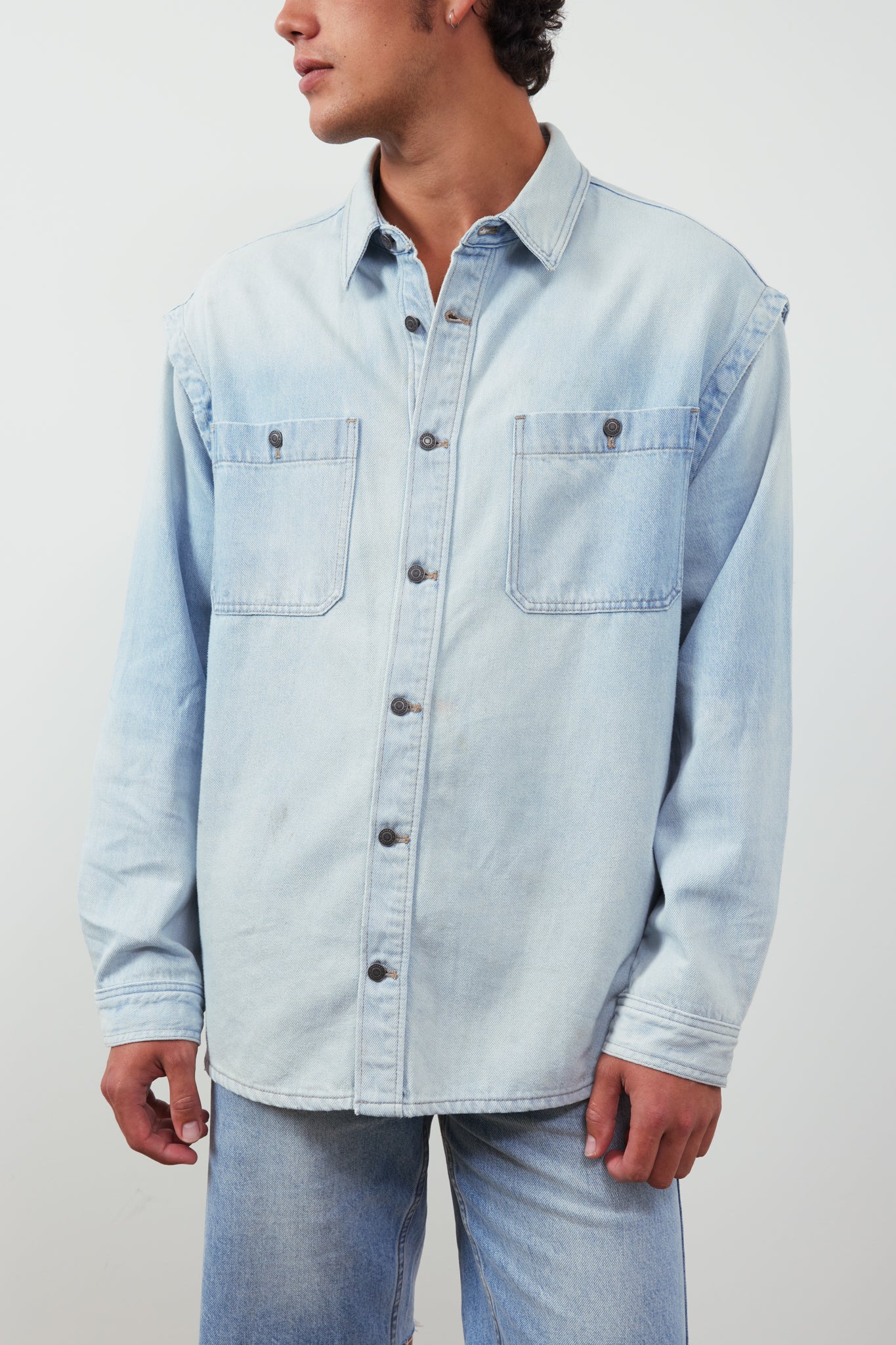 Light blue denim shirt worn by a person on a plain background