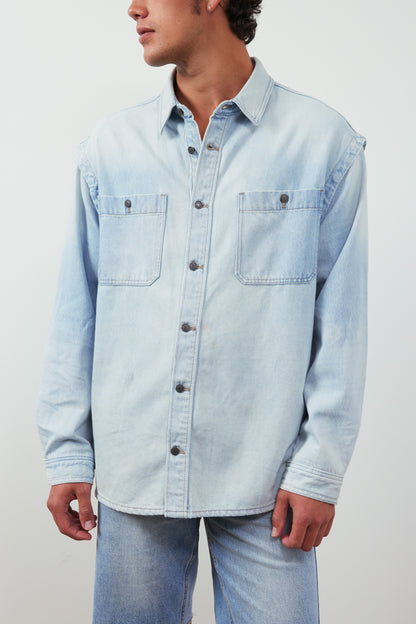 Light blue denim shirt worn by a person on a plain background